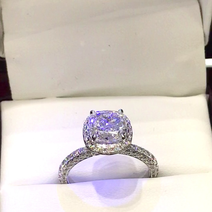 18kt White Gold Engagement Ring with 2.0 carat lab diamond at the center (Color: E | Clarity: VS1 | Cushion Cut) and natural E / VVS grade Setting Diamonds. Halo Setting with three side Diamonds on the Shank and Petal cut Design beneath the Center Diamond.